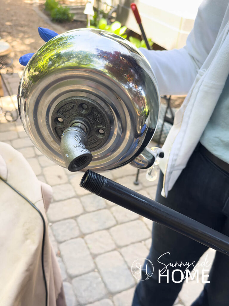 Woman threads pipe on elbow that is attached to a teapot