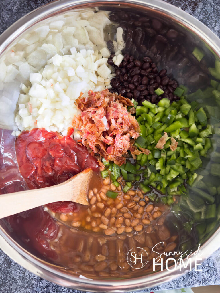 Ingredients for baked bean recipe: onions, pork and beans, black beans, green peper, bacon, ketchup.