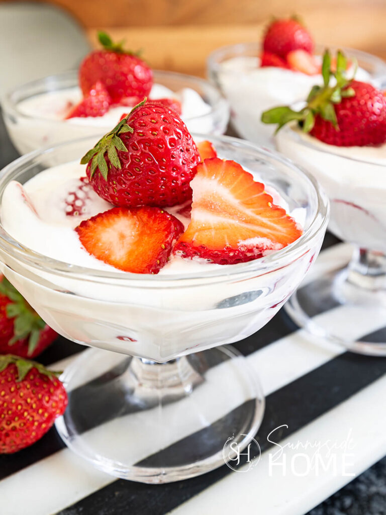 Fresas con crema in a glass dessert dish garnished with fresh strawberries.