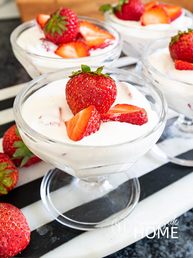 Fresas con crema in a glass dessert dish garnished with fresh strawberries.