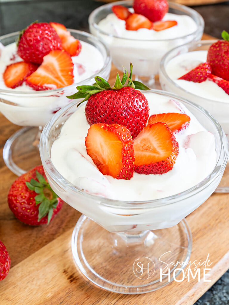 Fresas con crema in a glass dessert dish garnished with fresh strawberries.