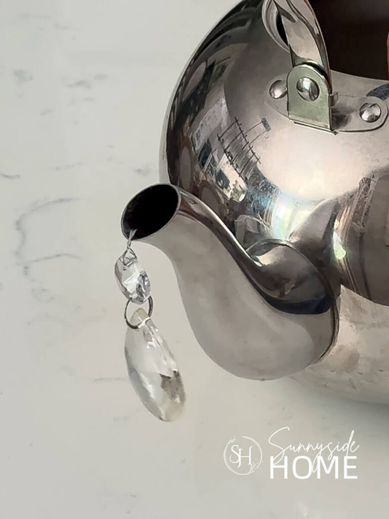 Crystal piece is attached to the spot of a teapot with wire.