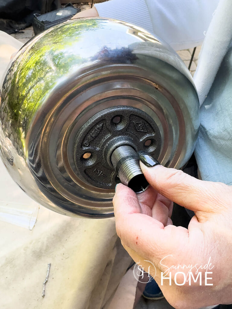Woman threads nipple onto flange that is attached to a teapot.