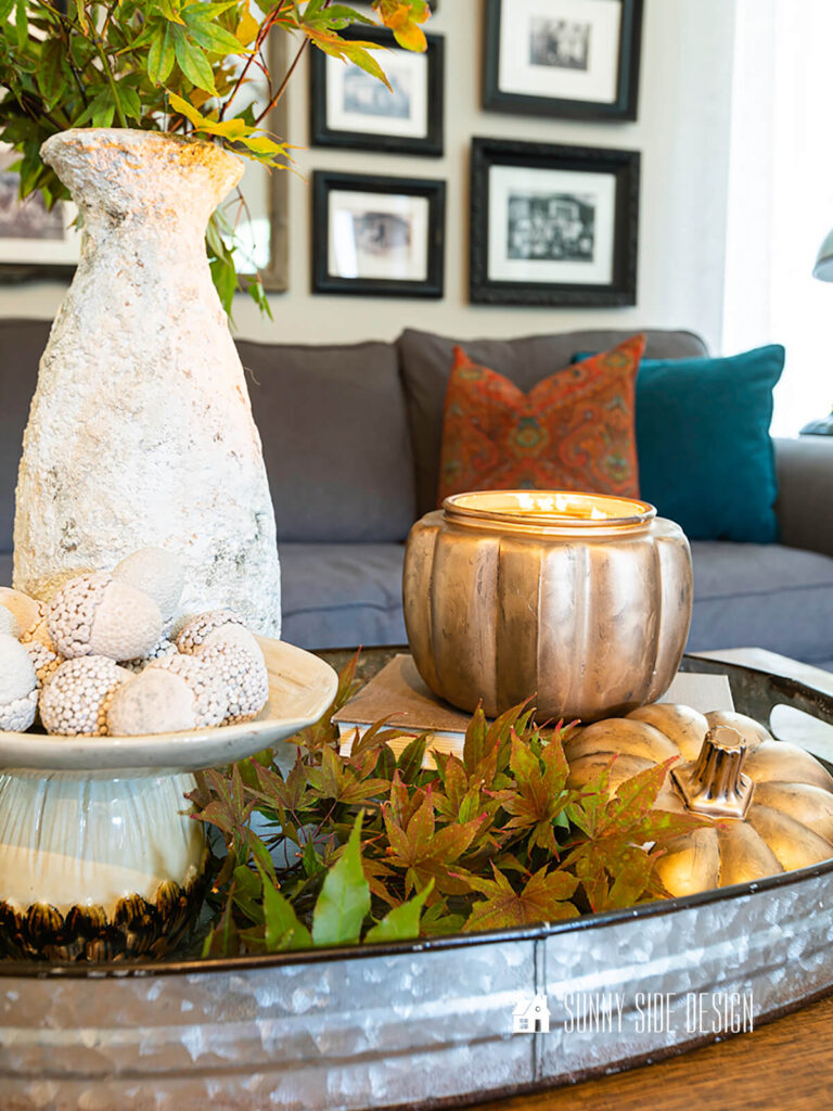 Anthropologie dupe, gold pumpkin candle, styled with maple leaves and acorns.