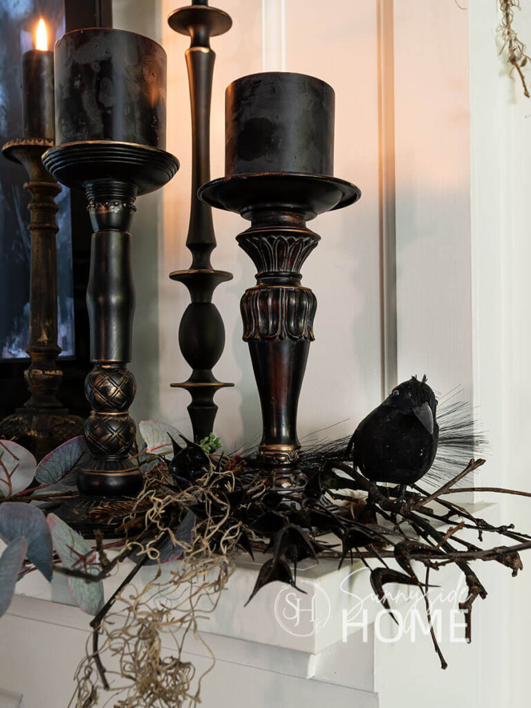Thrifted black candlesticks with glowing black candles, twigs, eucalyptus, feathers and black birds.