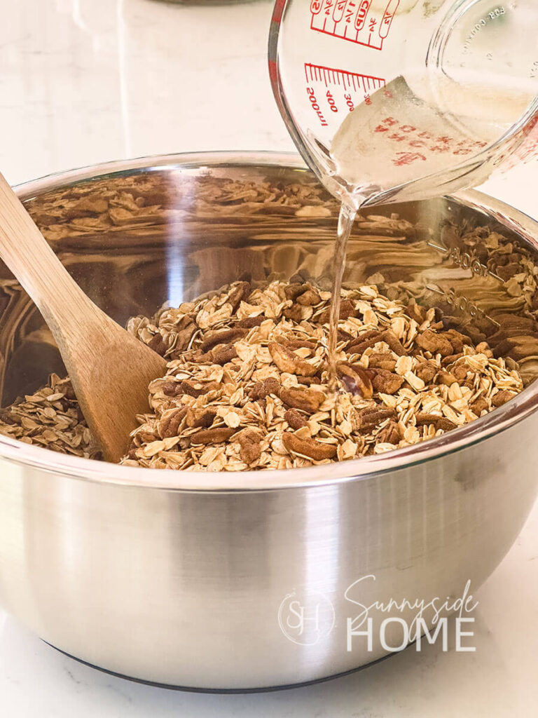 Melted coconut oil and vanilla is poured over the combined dry ingredients for homemade granola.