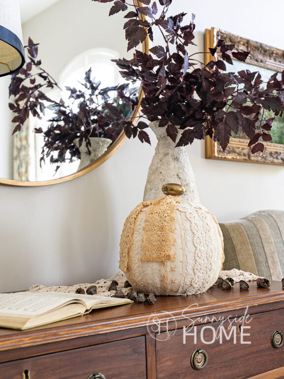 Vintage lace pumpkin decor with an old brass door knob stem, styled on a vintage dresser.
