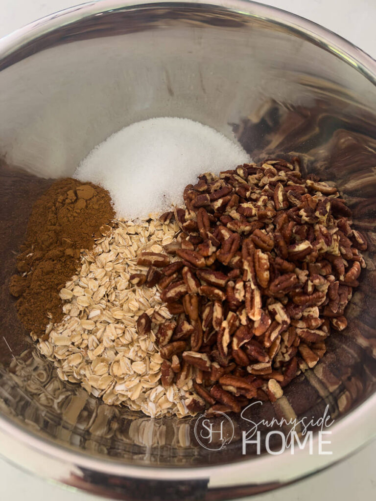 Dry ingredients in a stainless steel bowl for pumpkin spice granola.