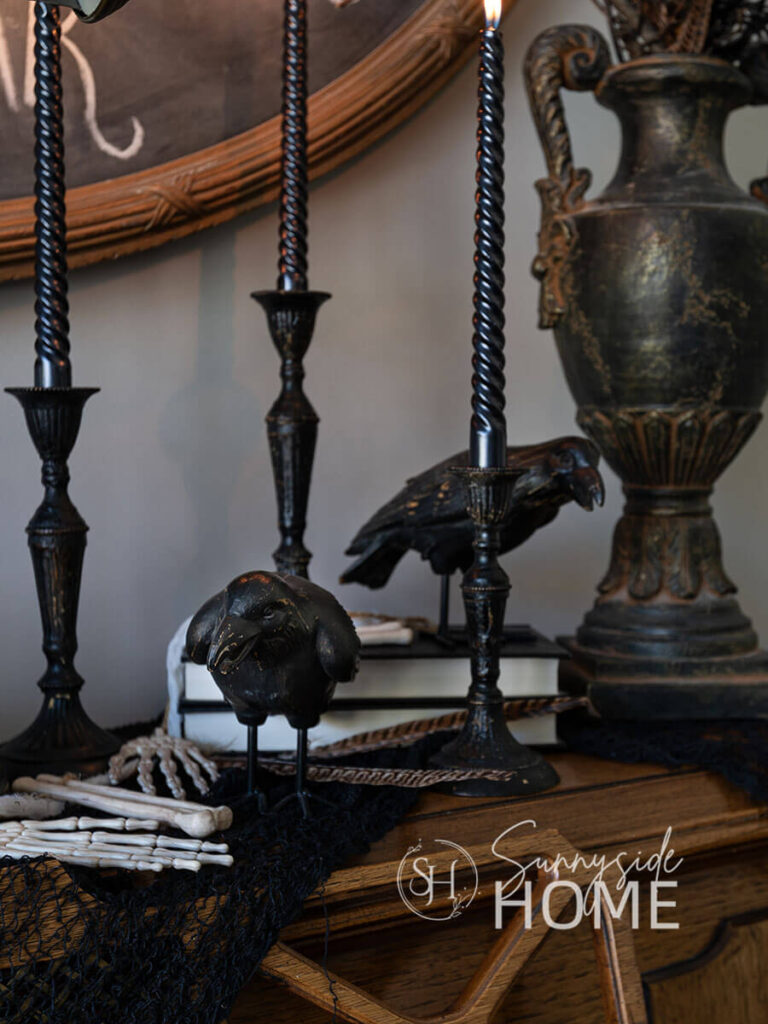 Raven placed on a book stack with a garland of bones and a vintage black vessel.