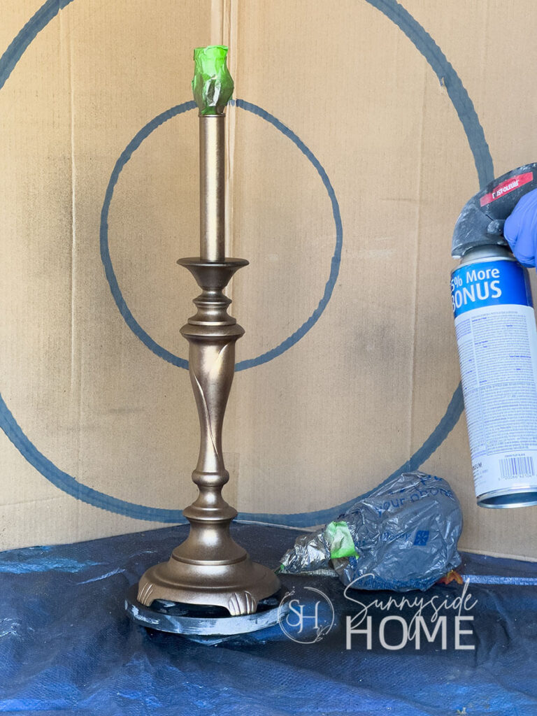 Woman applies a light dusting of black paint to achieve the faux antique brass finish.