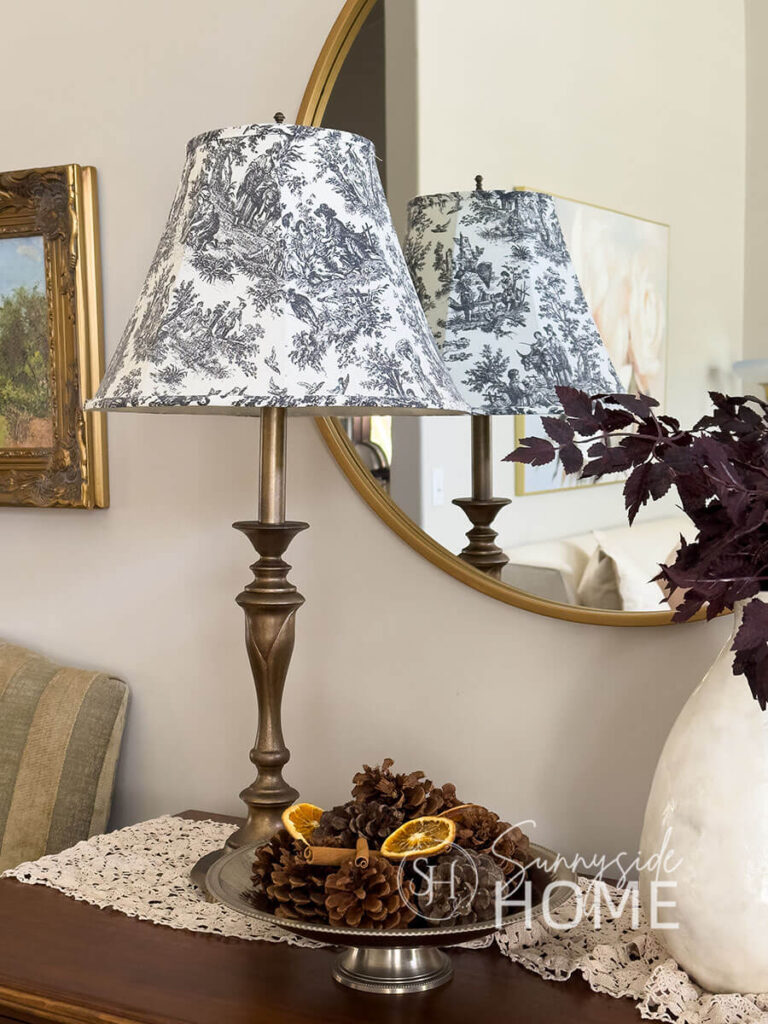Faux antique brass finish on a thrift store lamp base with a toile lamp shade on an entry table.