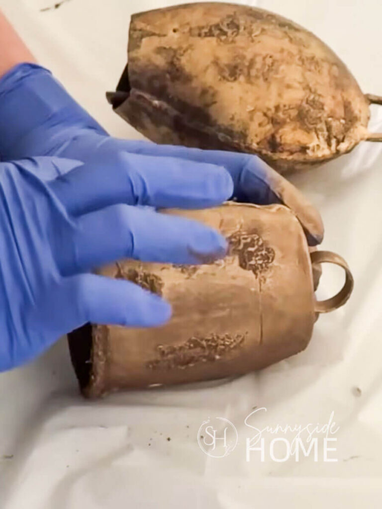 Woman applied a second coat of European gold Rub 'n Buff to bell made from recycled materials.