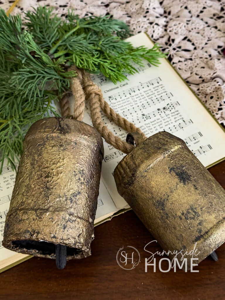 Styled DIY Christmas bell on a Christmas hymn book with greenery.