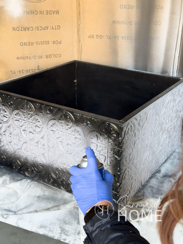Woman applies black spray paint to DIY Christmas tree collar.