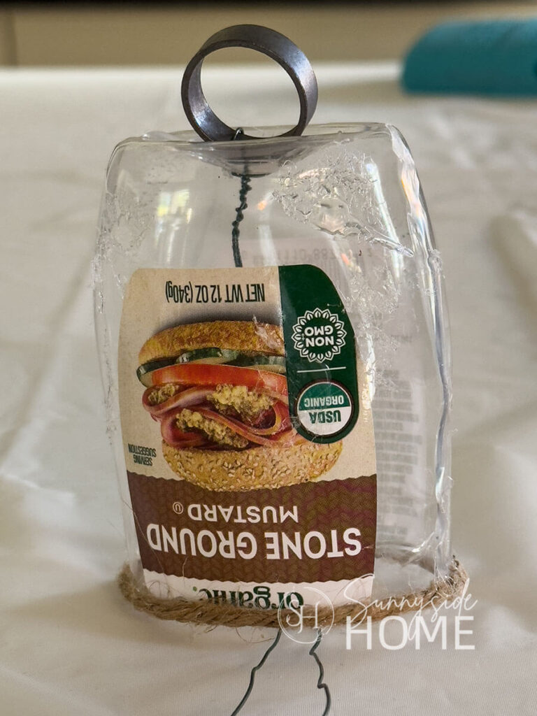 Recycled mustard container with a ring wired to the top, dabs of hot glue for texture and jute attached to the bottom of the container for DIY bell.