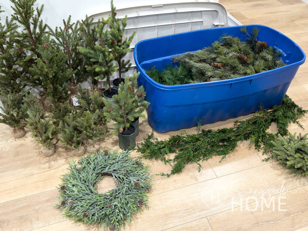 A large plastic tote store faux Christmas greenery, wreaths and trees.