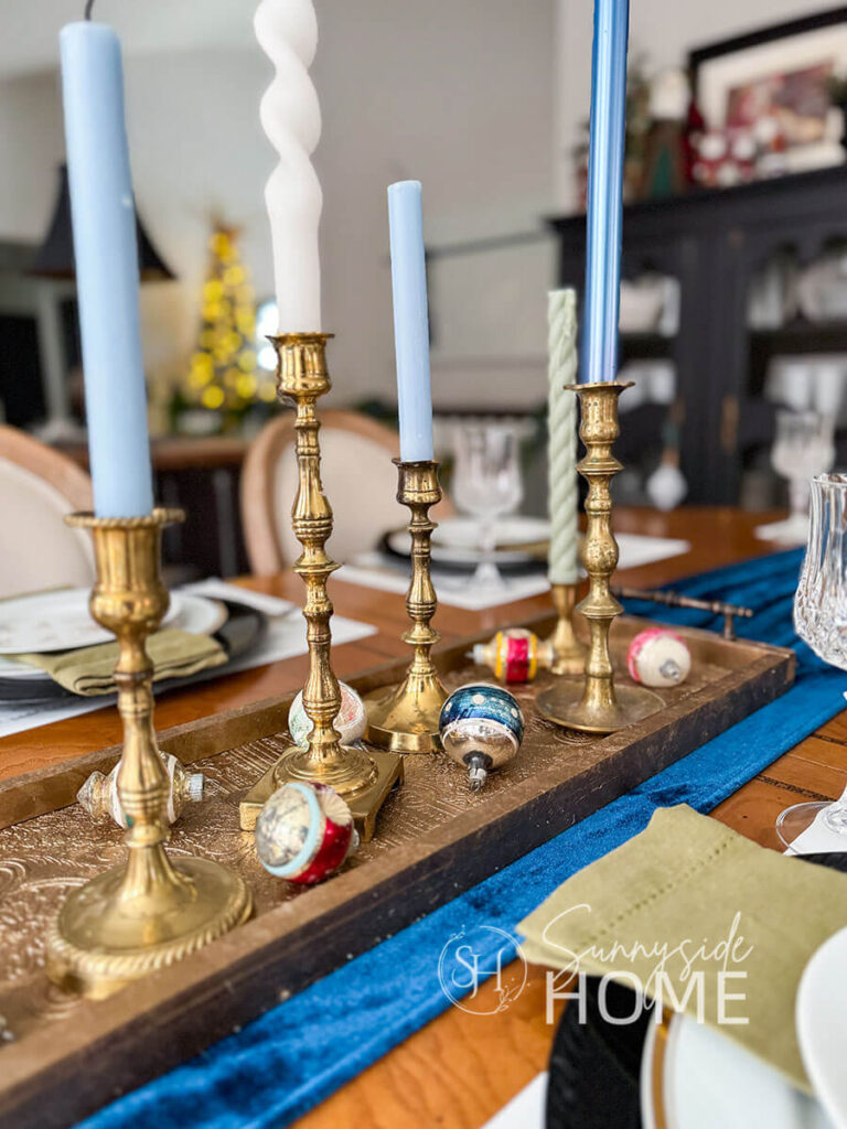 Dining table centerpiece: thrifted faux antique brass tray with embossed wallpaper, thrifted brass candlesticks and vintage glass ornaments.