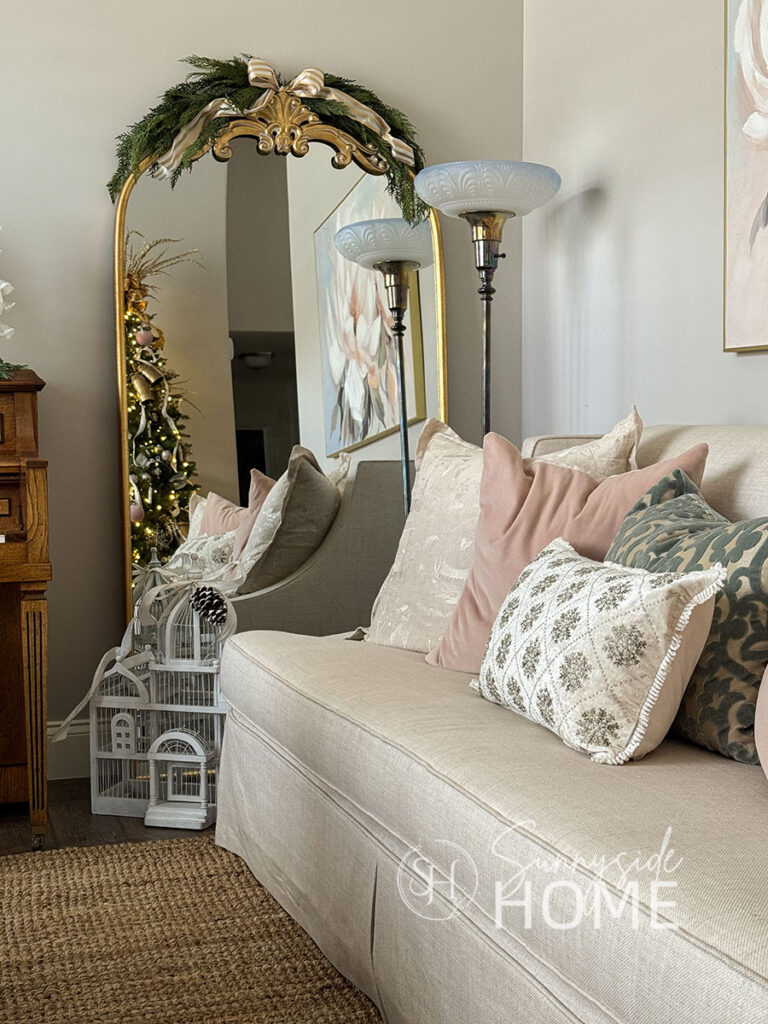 Floor mirror reflects the decorated Christmas tree, topped with a cedar swag embellished with a white and gold bow.