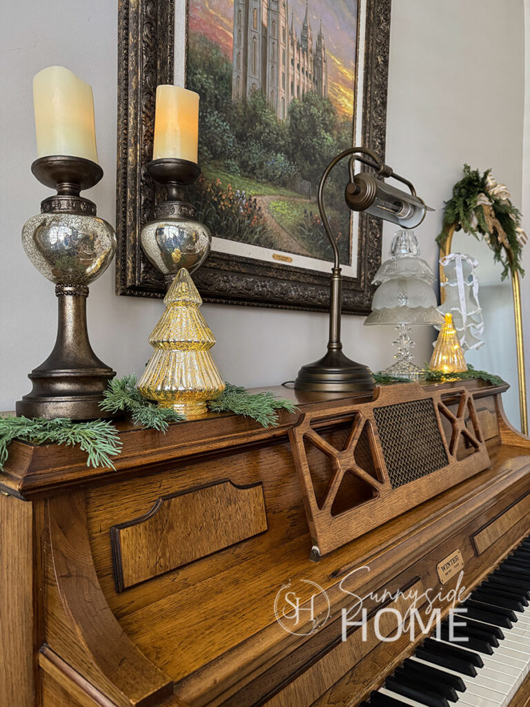Piano is decorated with candles, lighted glass trees and DIY glass bowl trees.