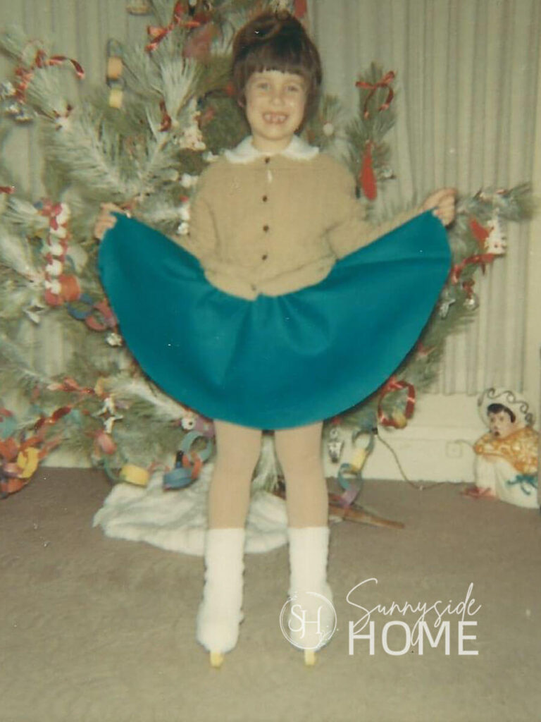 Young girls standing in front of the Christmas tree wearing her new Ice skate outfit.