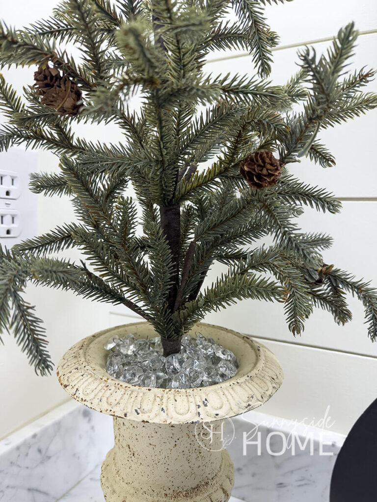 Chandelier crystals are used to cover the styrofoam in this container with a pine tree.