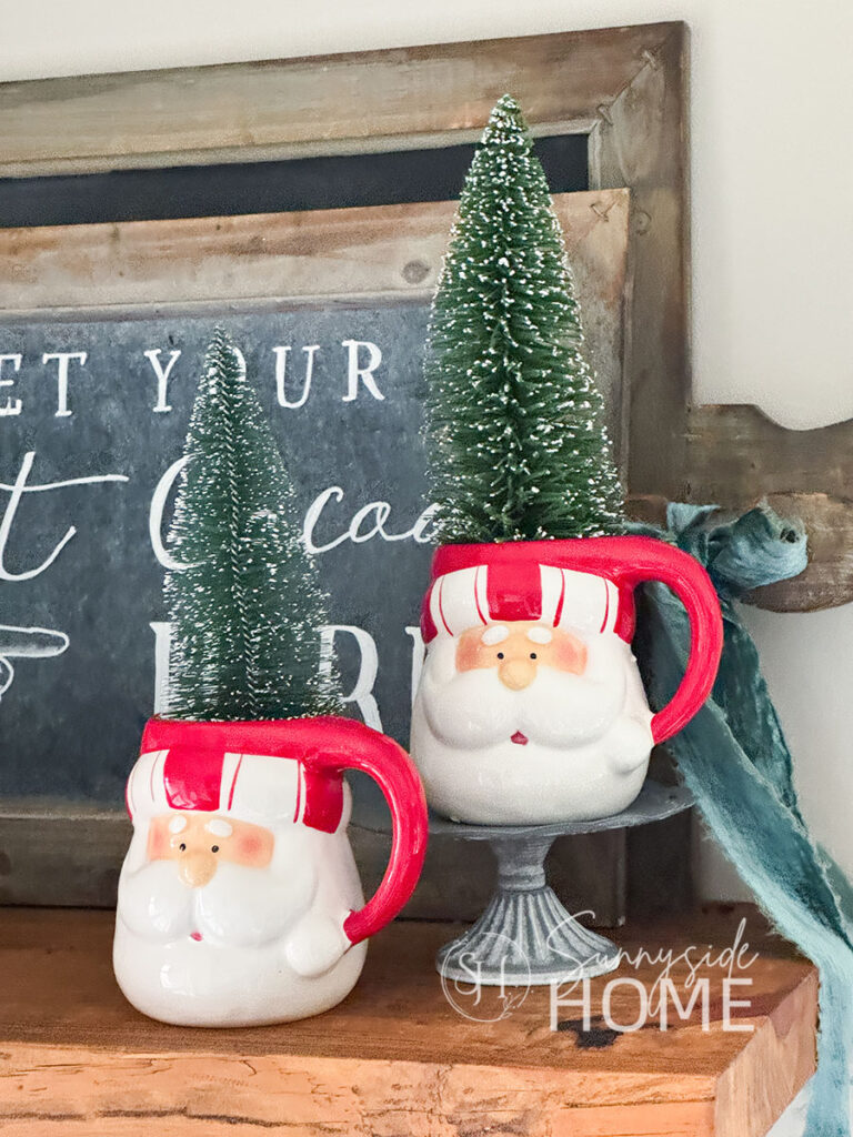 Green sisal trees in Santa mugs on a shelf in the kitchen.