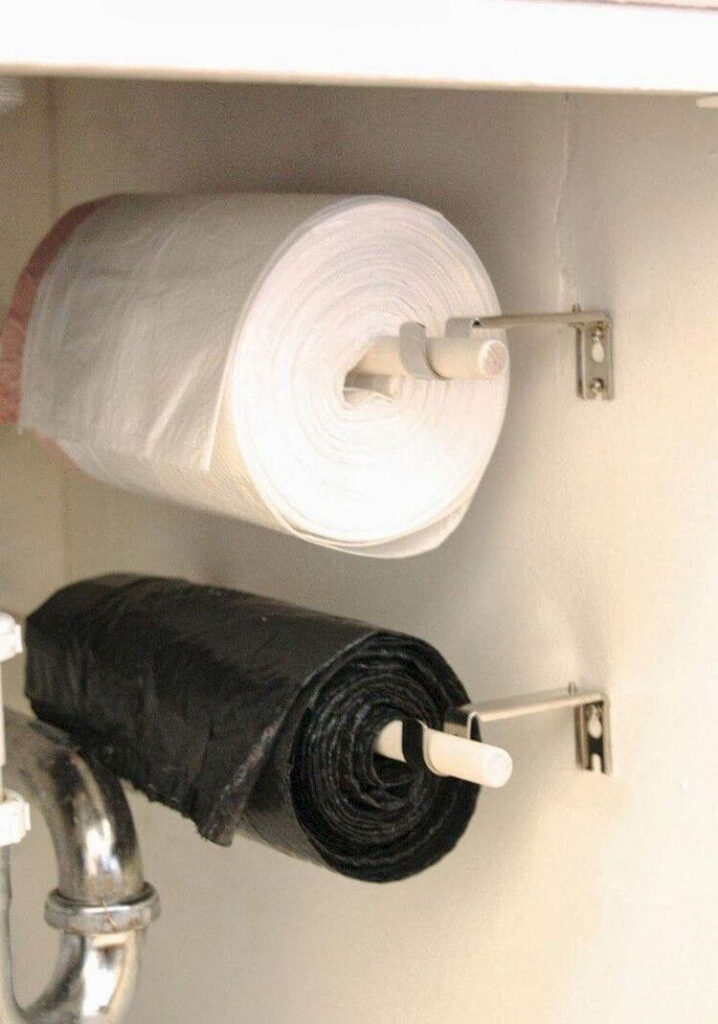 Trash bags are hung on a dowel with curtain rod brackets mounted to the side of the cabinet under the kitchen sink.