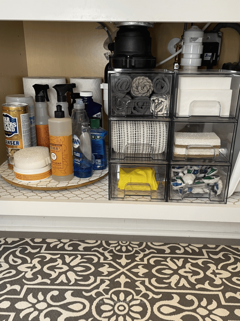 Shallow clear storage pullout bins organize kitchen products around the garbage disposal.