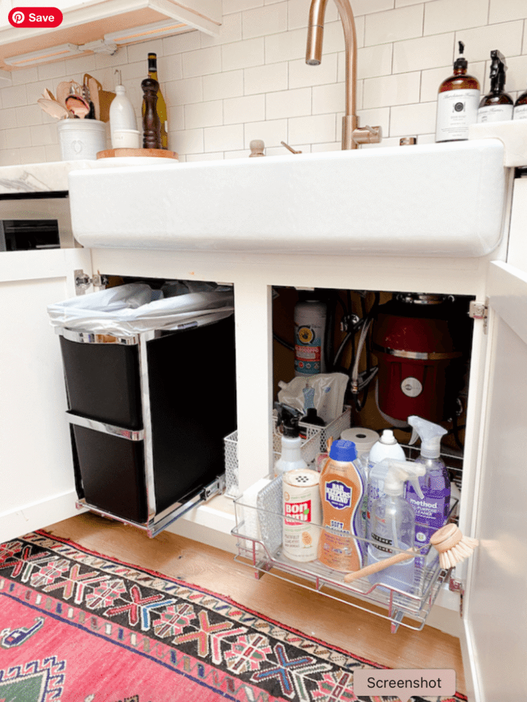 A pullout trash can is mounted under the kitchen sink along with other clear kitchen organizing containers.