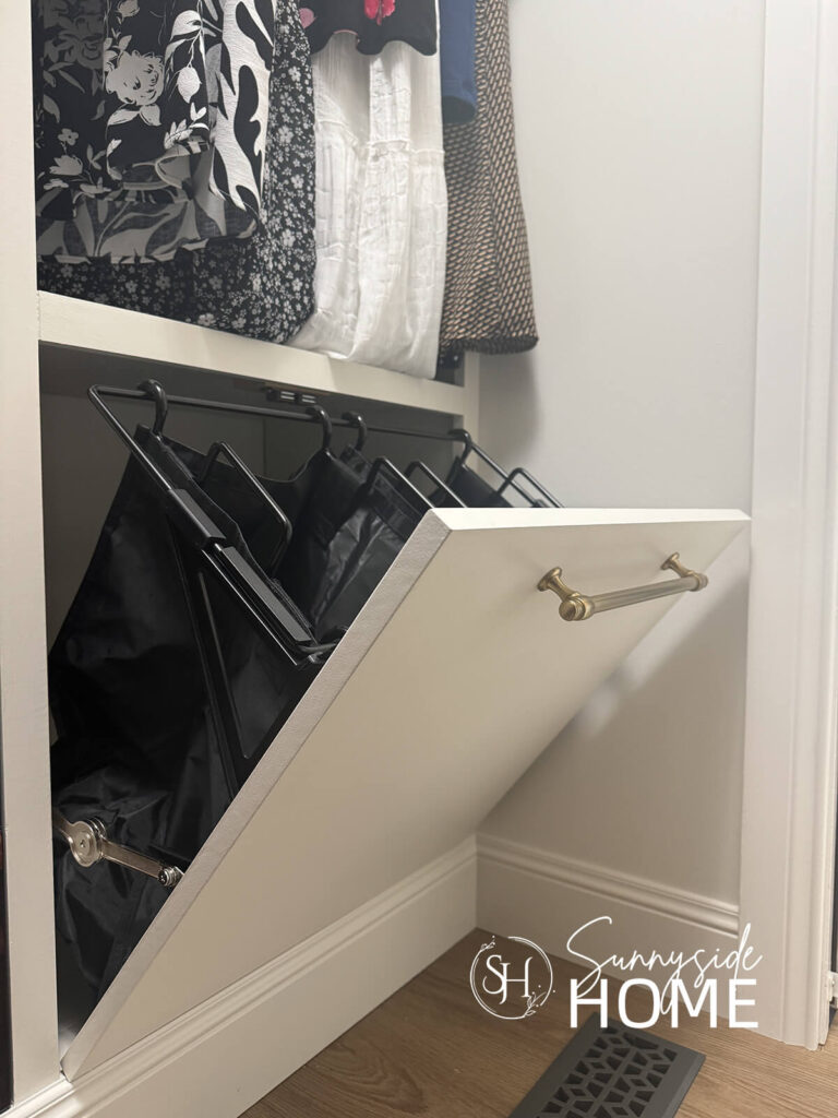 Inside a walk-in closet with the tilt-out hamper pulled open for easy ways to keep your bedroom neat and tidy,