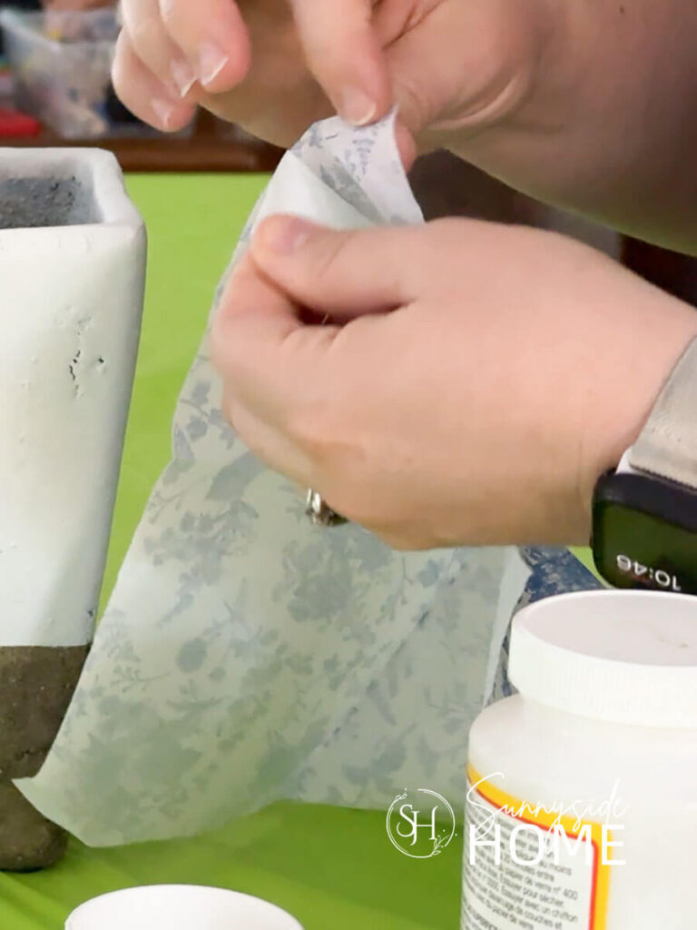 A woman separates the plys of a blue an white napkin.