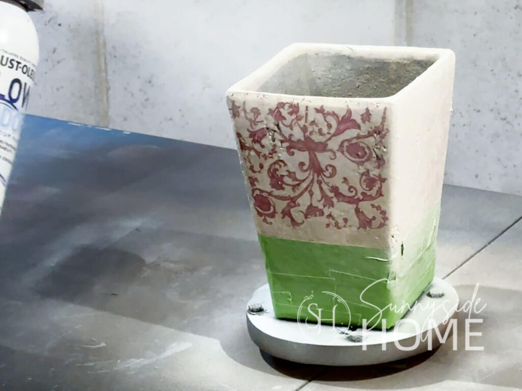 Spray paint is applied to an old forgotten vase.