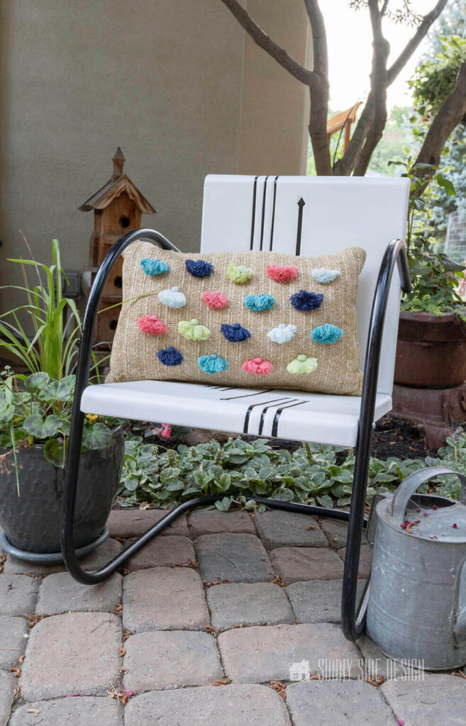 Vintage metal chair with a tassel pillow on the patio under the maple tree.