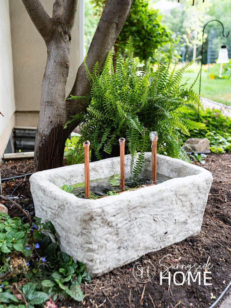 Backyard ideas: create a water feature with a DIY faux limestone garden fountain with copper pipes and pond plants.