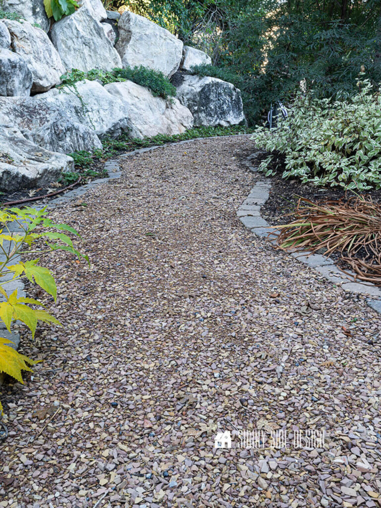 Crushed flagstone garden path lined with pavers along a rock retain wall and dogwood.