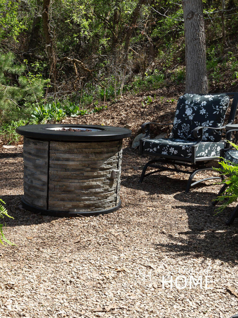Fire pit with outdoor chairs with black foral cusions.