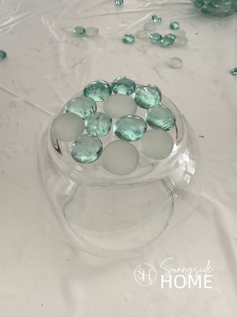 Glass gems are adhered to the bottom of a round glass base with clear silicone.