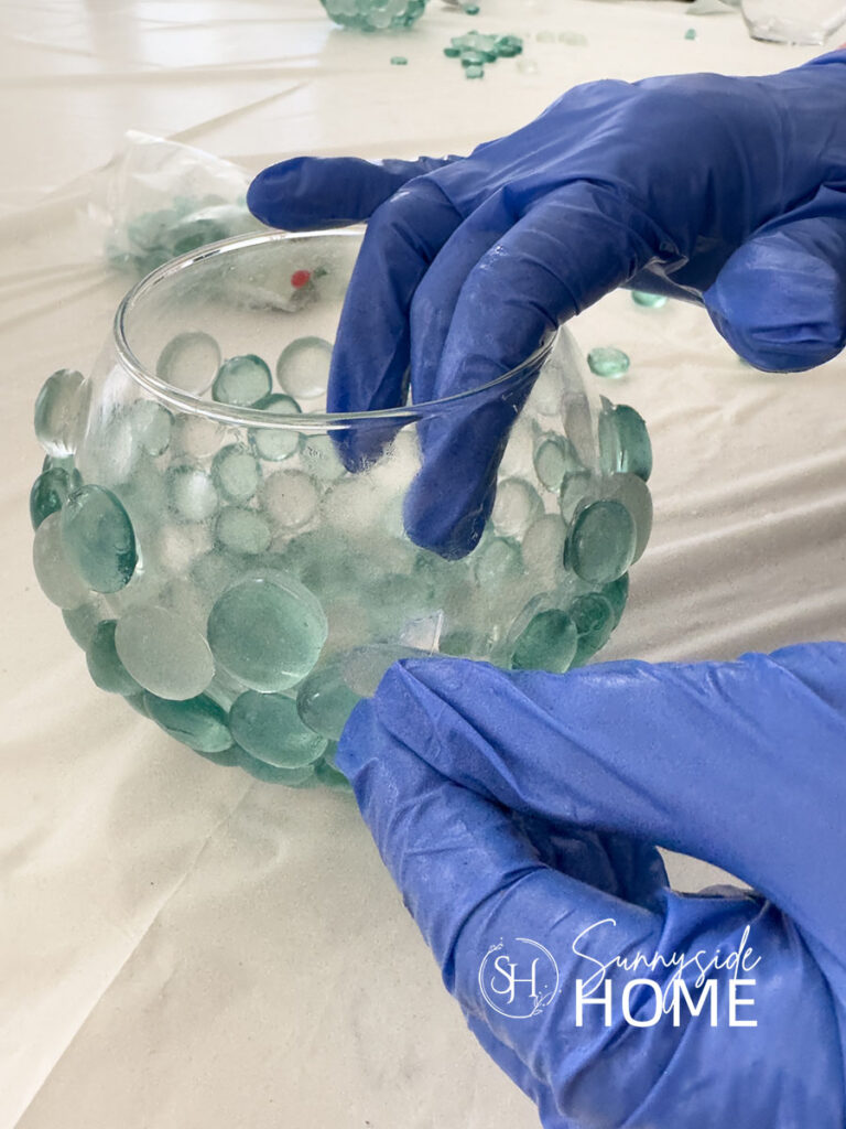Woman pressed glass gem with silicone to a round glass vase.