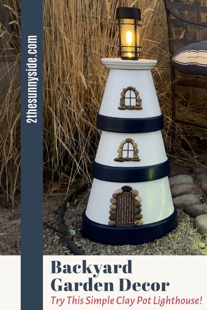 Pinterest image at dusk a lit clay pot lighthouse styled in the garden with natural grasses.