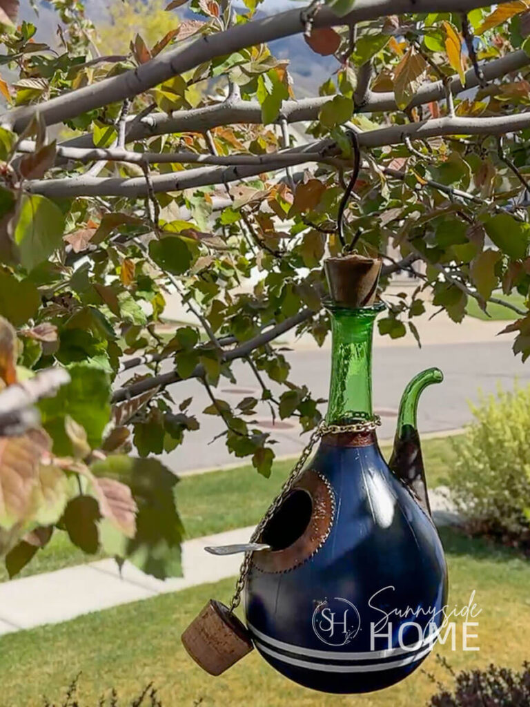 Final How to Make a Birdhouse with Thrift Store Finds, a wine decanter is upcycled with paint for a whimsical garden birdhouse.