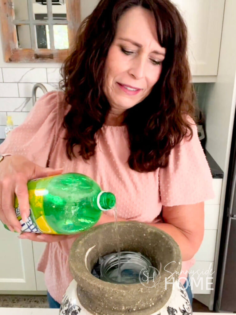Woman adds a splash of lemon-lime soda into a vase to help make peonies last longer a vase.