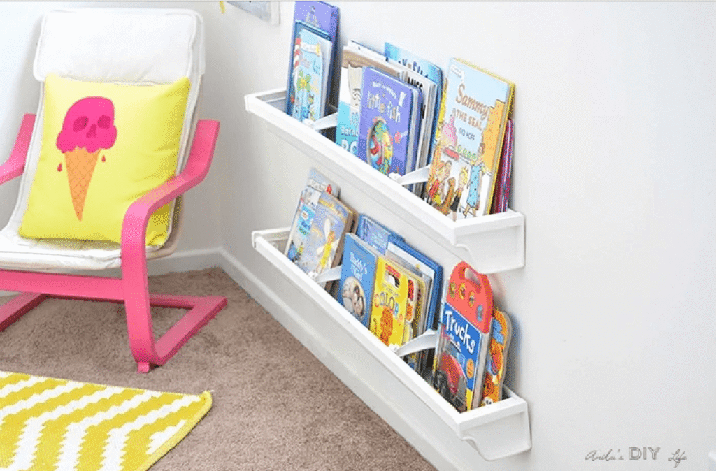 In a toy room a reading corner is created with a colorful child's chair and wall mounted rain gutter bookshelves.