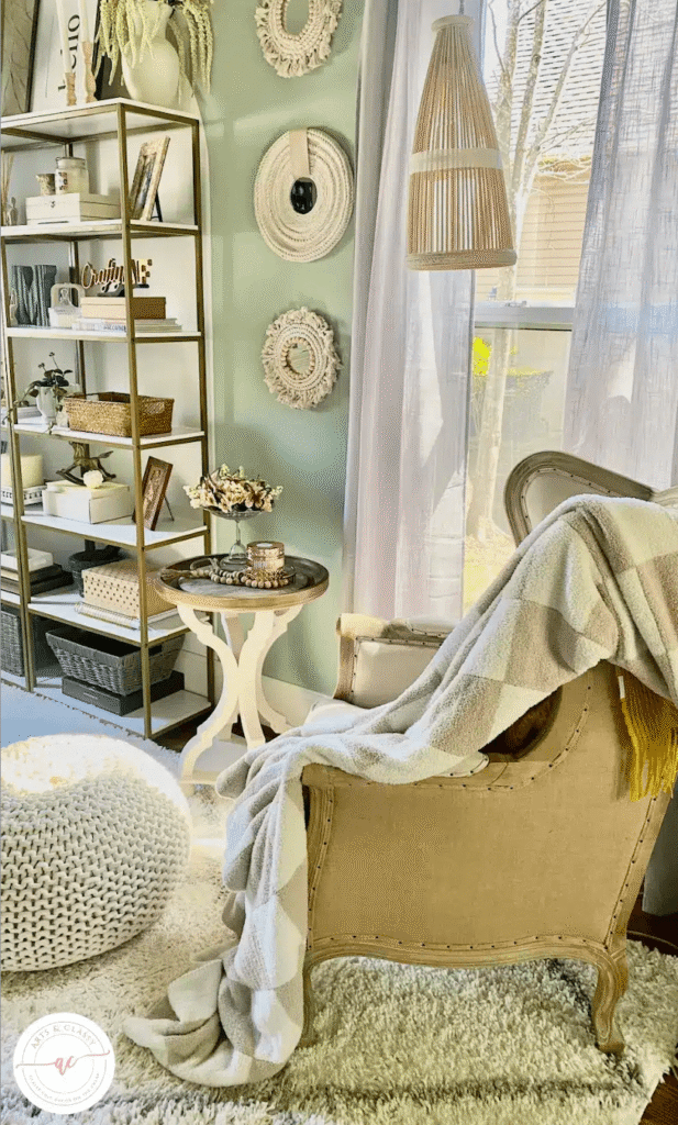 Simple reading nook ideas with a cozy chair, pouf, throw blanket, side table, hanging lamp and bookshelves.