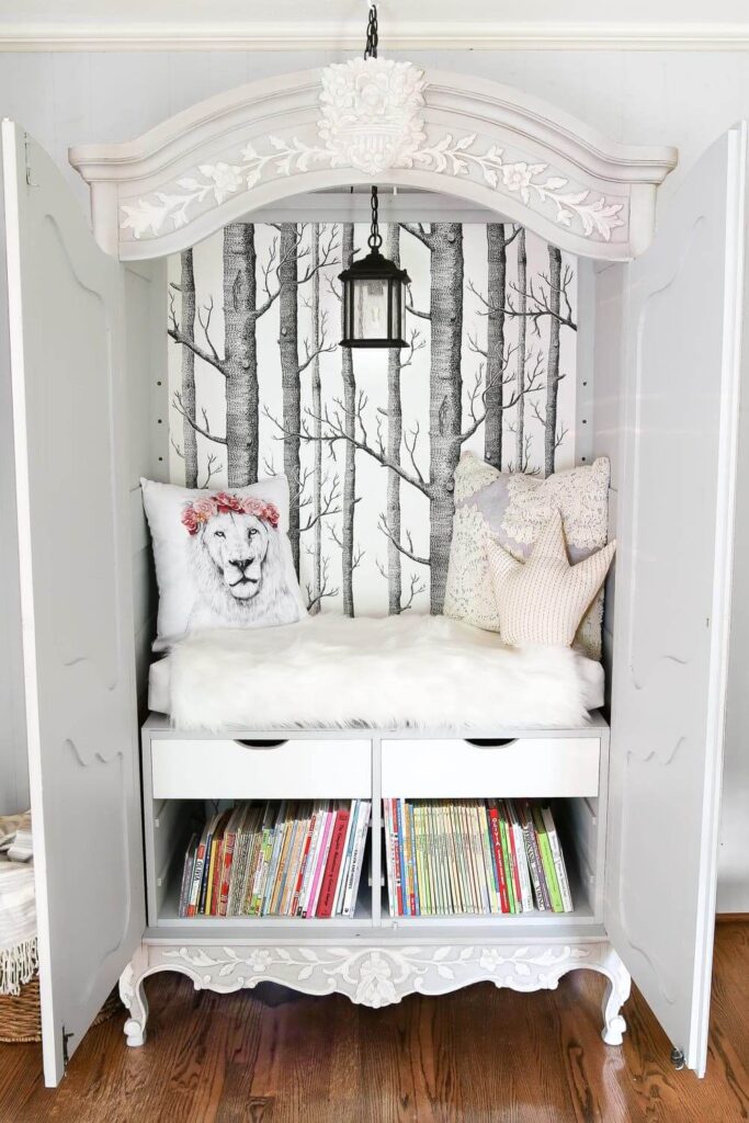 An old armoire is turned into a cozy kids reading nook with paint, wallpaper, light,cushion and cozy pillows.