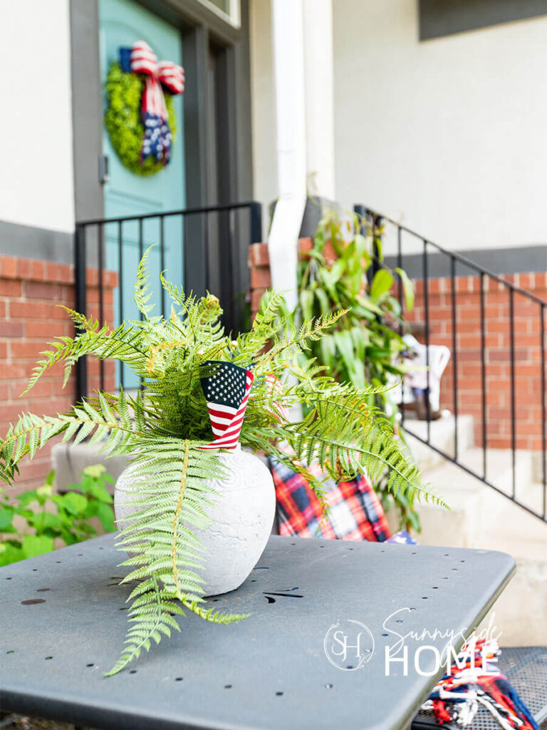 A concrete pot with a fern is embellised with patriotic flags.
