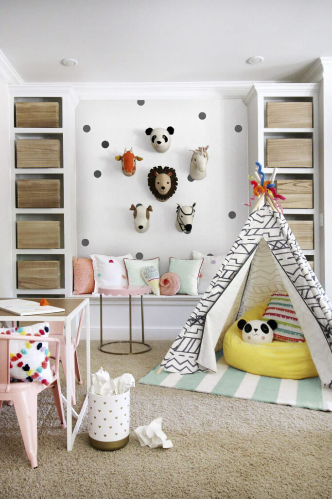 A cozy reading space is created with a striped rug, yellow pouf, pillow under a play tent.