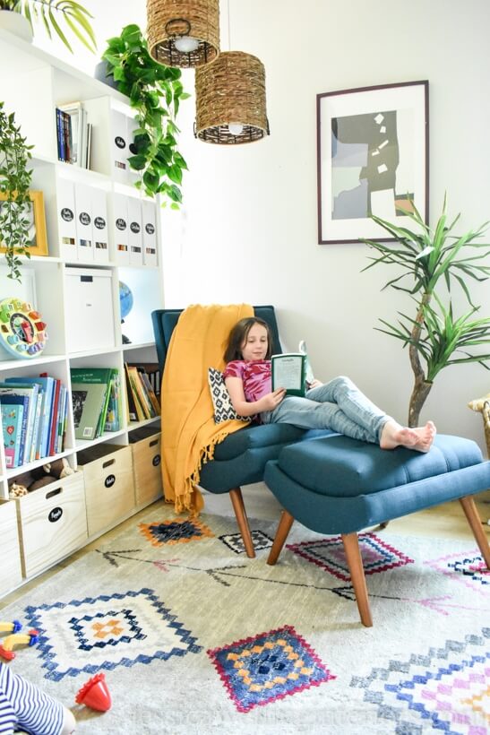 A reading nook ideas. paritioning part of a living room with an Ikea book case, adding a cozy modern rug and a chair and ottoman.