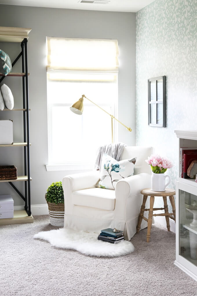 Simple reading nook ideas with a cozy chair, faux fur rug, throw pillow, side table, floor lamp and bookshelves.