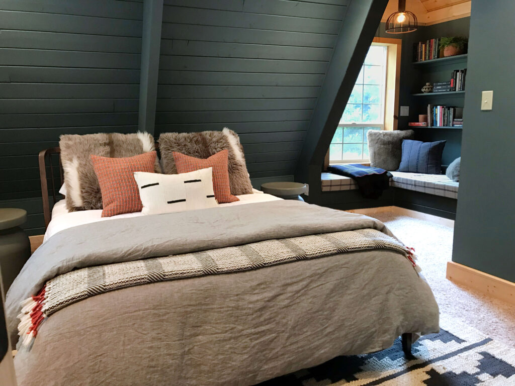 An awkward corner in a bedroom is turned into a cozy reading nook with padded bench and open shelves.