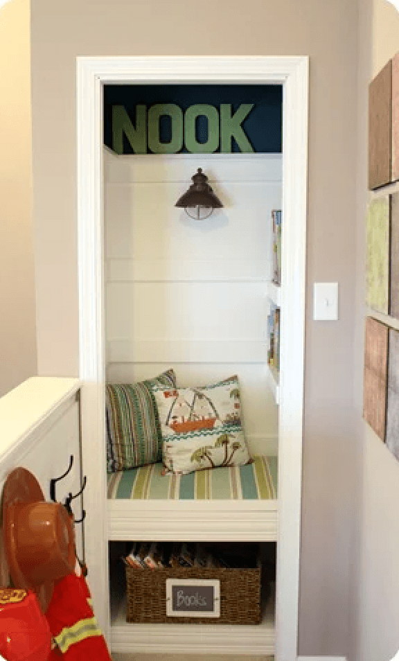 A tiny closet is converted to a cozy reading nook with a striped cushion, pillows, wall scoune and shelved mounted to the wall. This is the perfect place for a small child to explore picture books.